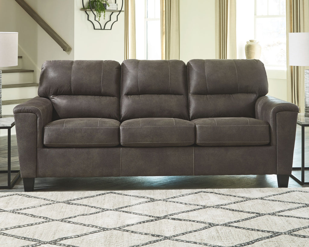 Dark gray sleeper sofa with tufted back, three seat sections, and tapered legs