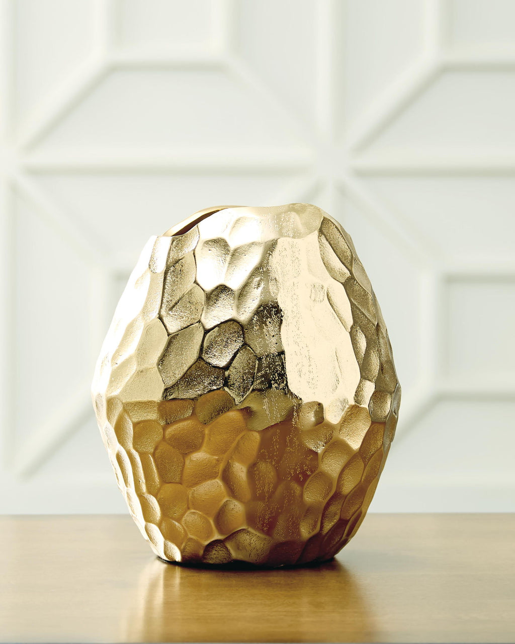 Gold hammered metal vase standing upright with rounded faceted body