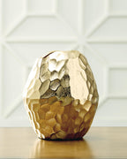Gold hammered metal vase standing upright with rounded faceted body