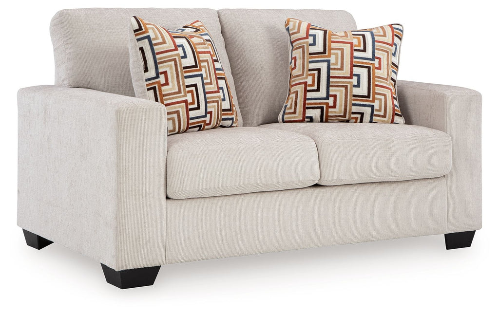 Light gray loveseat with two geometric patterned throw pillows, squared arms