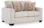 Light gray loveseat with two geometric patterned throw pillows, squared arms