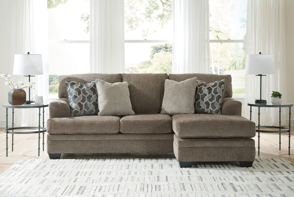 Light brown sectional sofa with chaise and multiple patterned accent pillows
