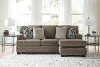 Light brown sectional sofa with chaise and multiple patterned accent pillows