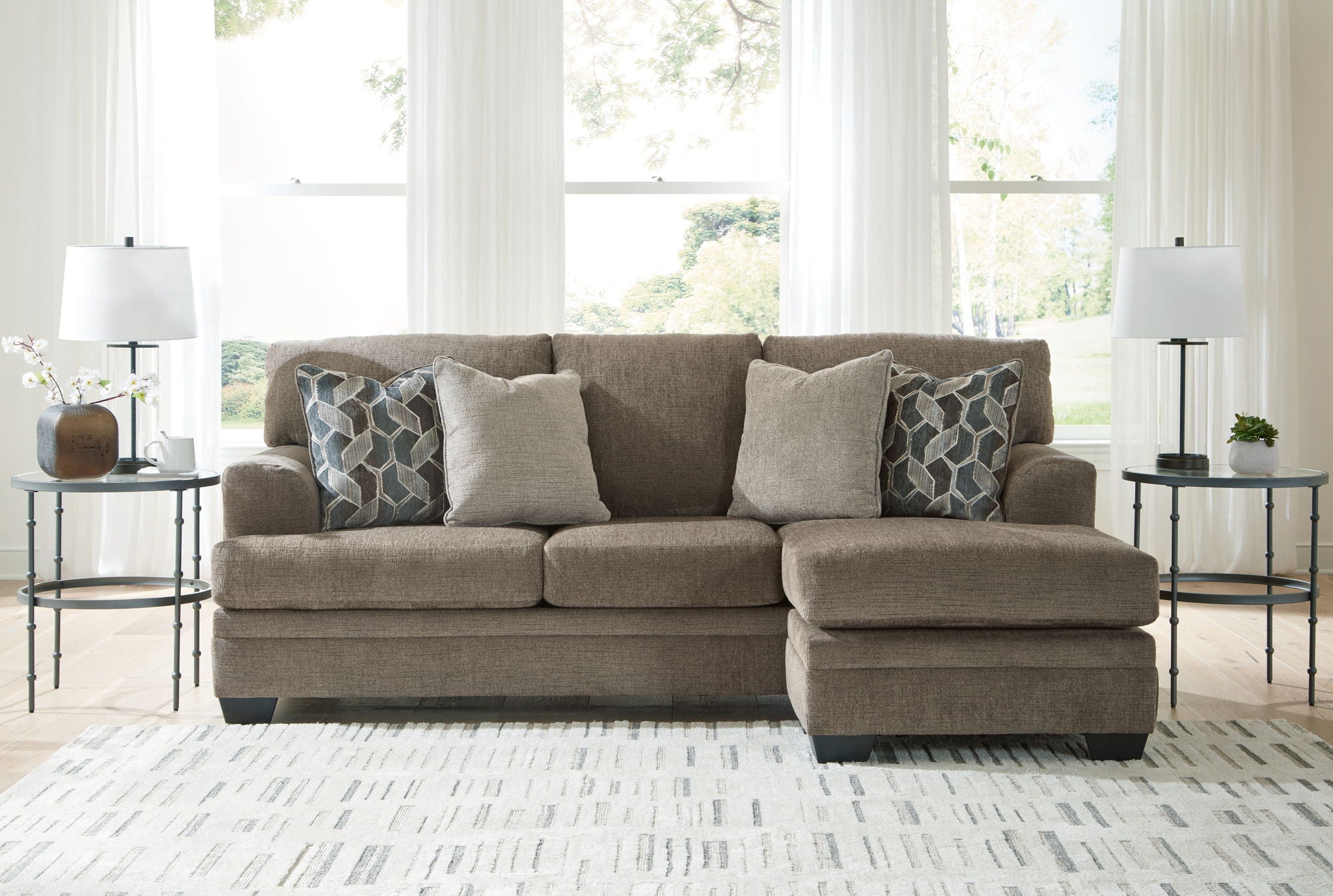 Light brown sectional sofa with chaise and multiple patterned accent pillows