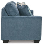 Blue fabric sofa back with multiple pillows stacked on the seat