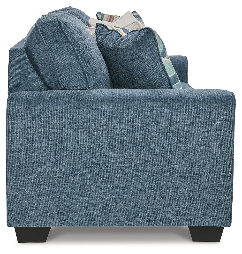 Blue fabric sofa back with multiple pillows stacked on the seat