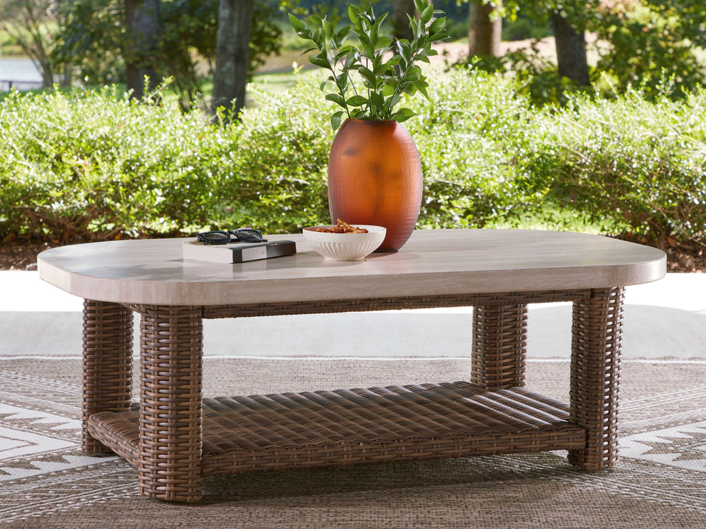 Rectangular cocktail table with light beige top and woven wicker frame, open storage shelf
