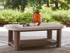 Rectangular cocktail table with light beige top and woven wicker frame, open storage shelf