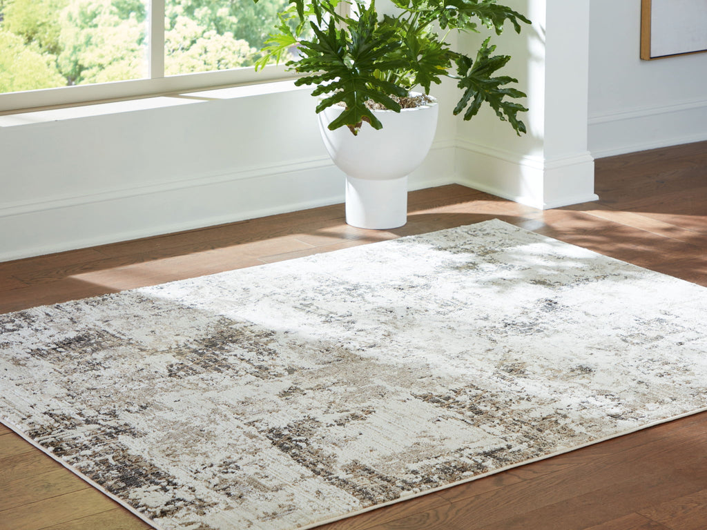 Corner view of distressed gray-and-beige area rug on hardwood floor.