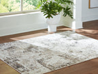 Corner view of distressed gray-and-beige area rug on hardwood floor.