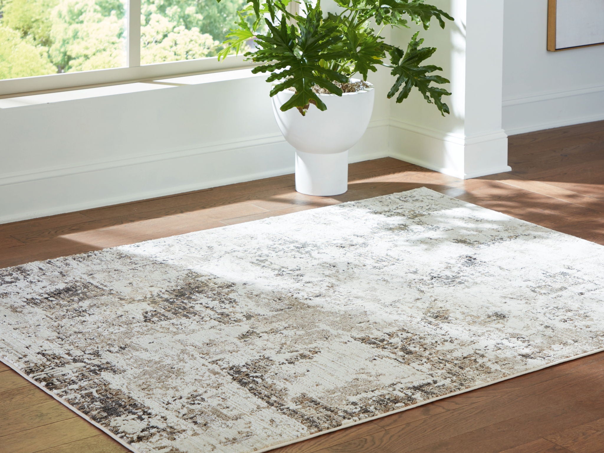 Corner view of distressed gray-and-beige area rug on hardwood floor.
