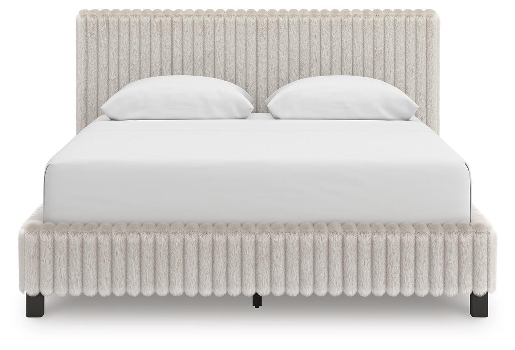 White upholstered bed with tall headboard, padded footboard, and two white pillows.