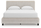 White upholstered bed with tall headboard, padded footboard, and two white pillows.