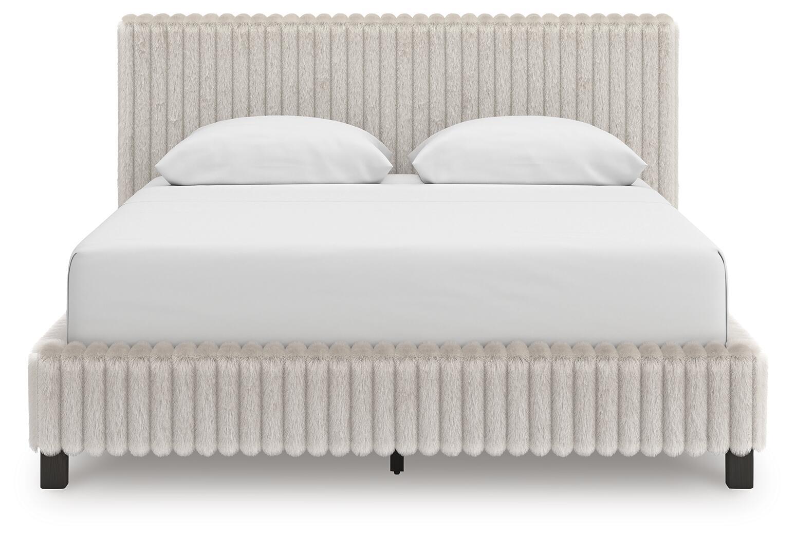 White upholstered bed with tall headboard, padded footboard, and two white pillows.