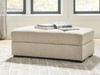 Lofwood Ottoman in beige fabric with a book stack on the padded top and black feet
