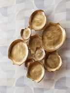 Antique gold wall decor of curved metal leaf discs, embossed texture, scattered
