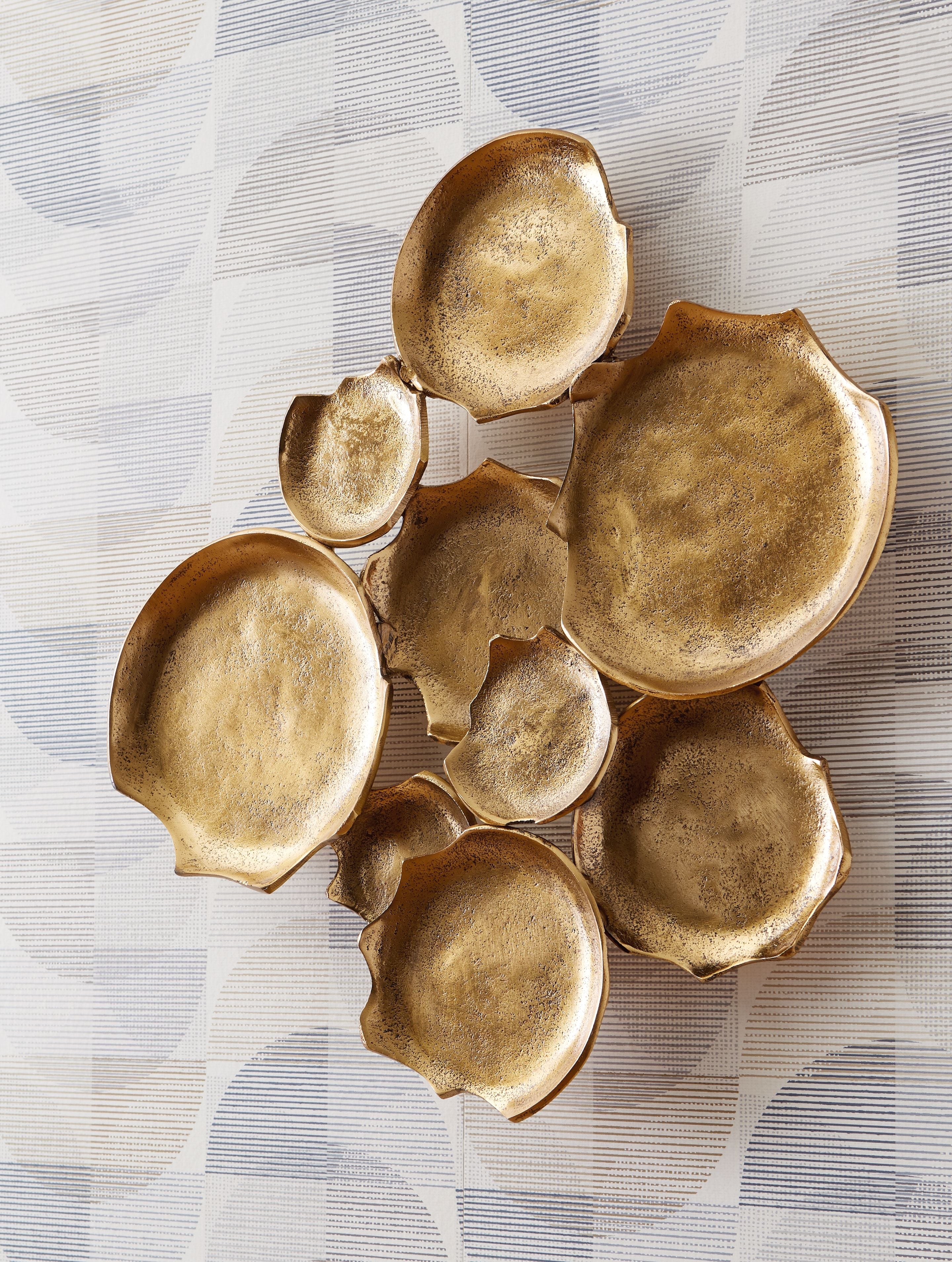 Antique gold wall decor of curved metal leaf discs, embossed texture, scattered