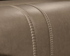 Taupe-brown upholstery with dotted texture paneling and stitched edge seams