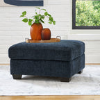 Navy upholstered accent ottoman with square top and dark block legs.