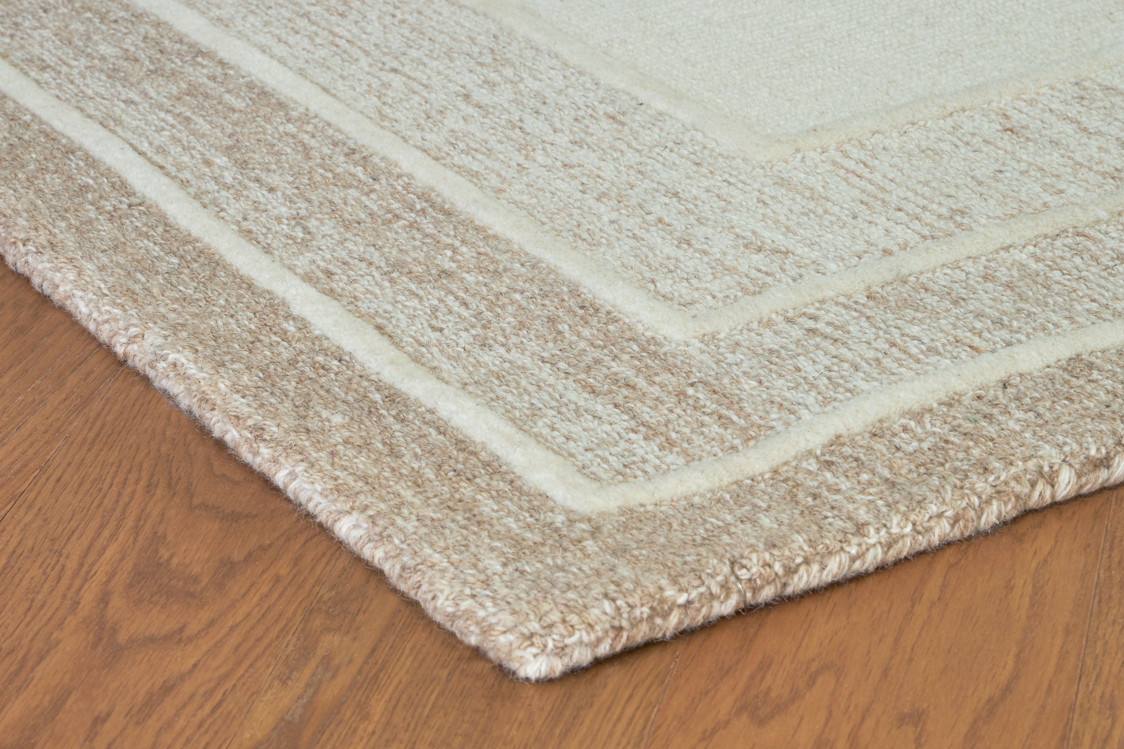 Beige rug corner with fringe trim and textured layered border design