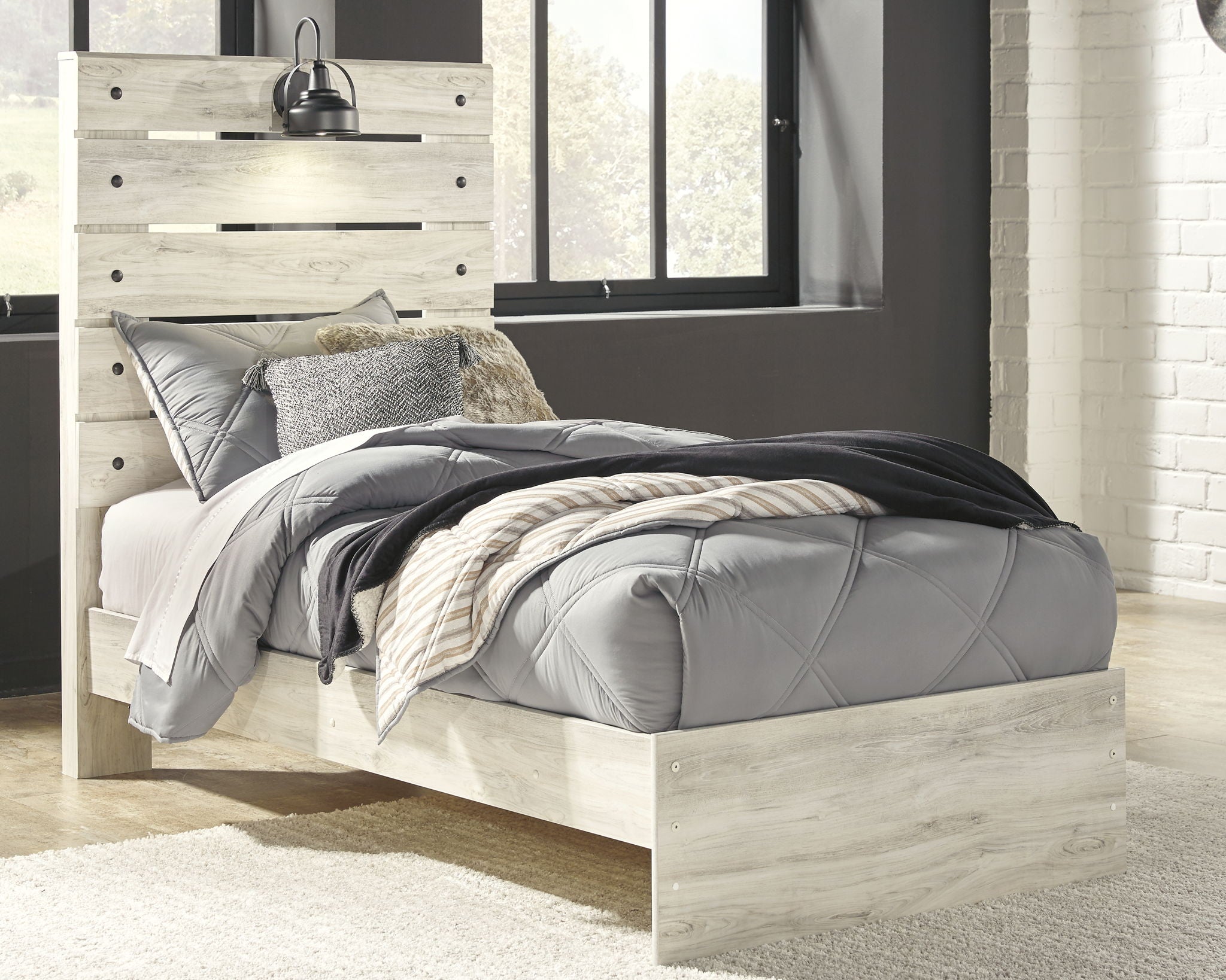 Light wood panel bed with upholstered headboard and gray bedding, with underbed drawers