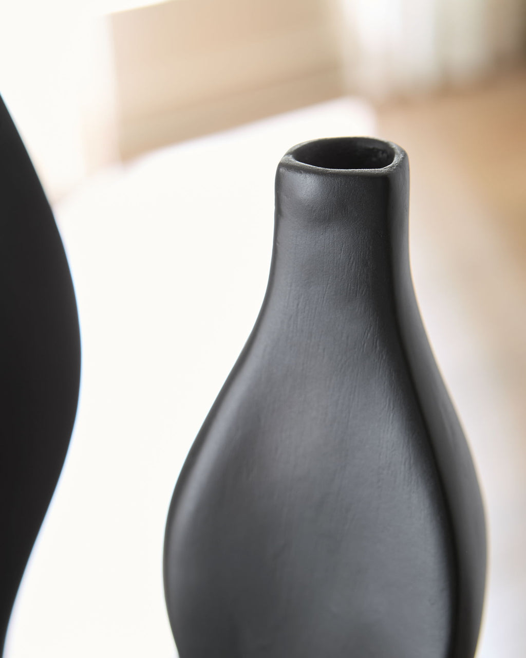 Black Judsen vase close-up with smooth matte texture and open top rim.