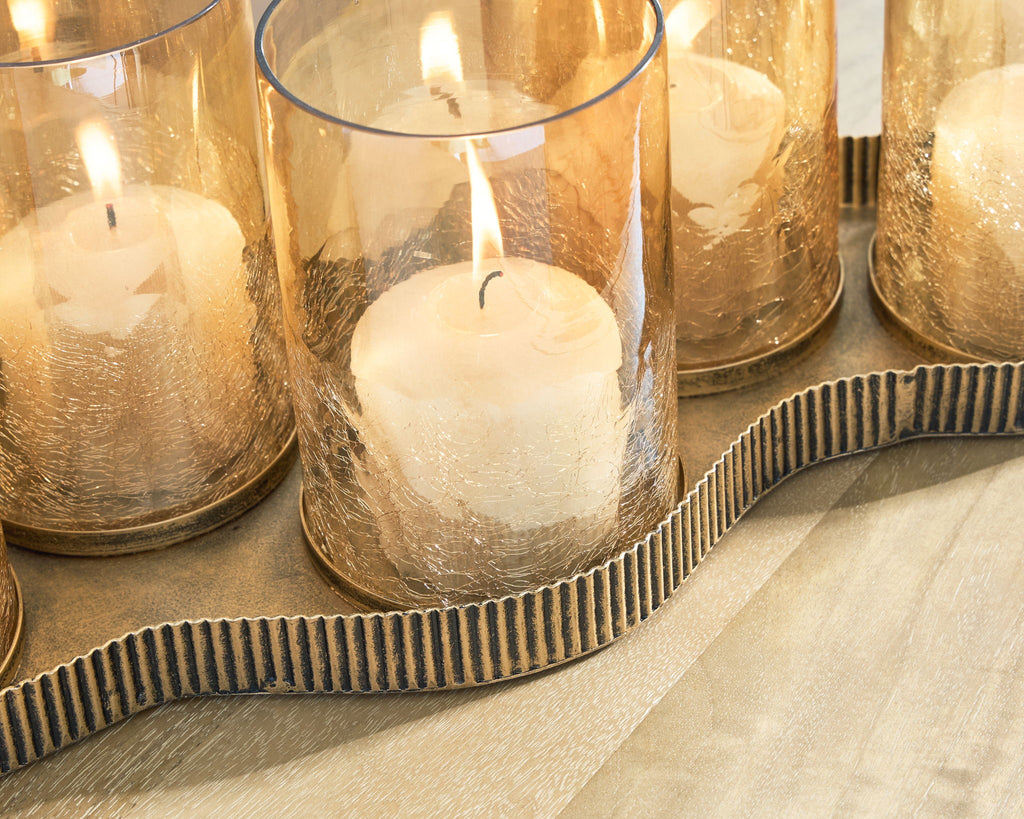 Antique gold candle holder close-up with lit wax candle in clear cylindrical glass cup
