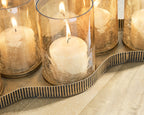 Antique gold candle holder close-up with lit wax candle in clear cylindrical glass cup
