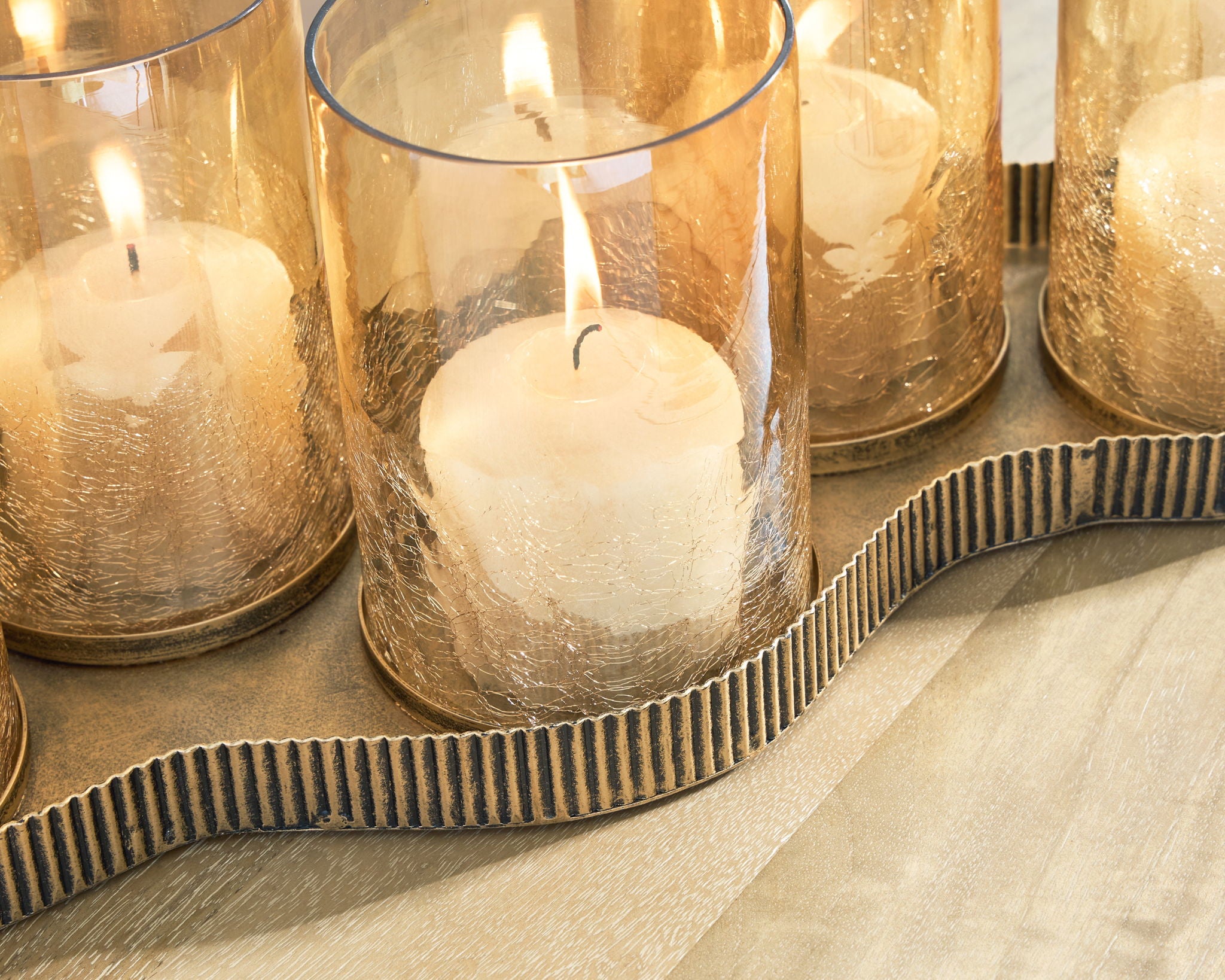 Antique gold candle holder close-up with lit wax candle in clear cylindrical glass cup