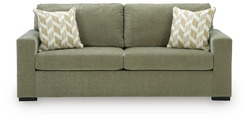 Green sofa sleeper with two patterned throw pillows and rounded armrests