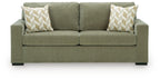 Green sofa sleeper with two patterned throw pillows and rounded armrests