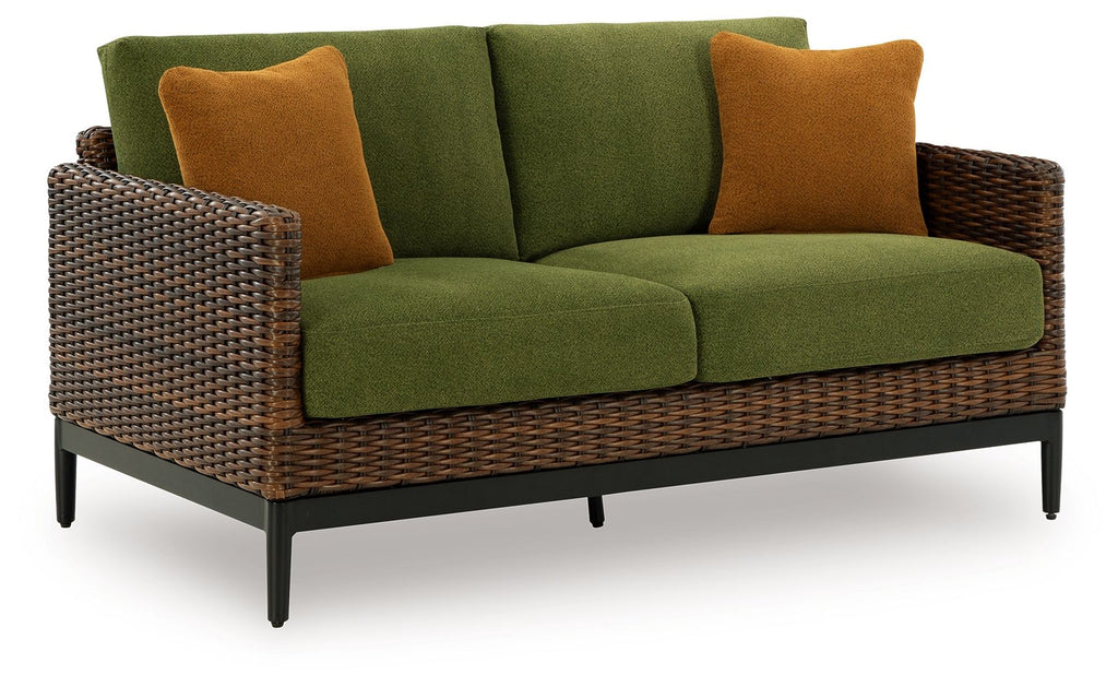 Outdoor loveseat with green cushions, brown woven arms, and two brown accent pillows