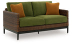 Outdoor loveseat with green cushions, brown woven arms, and two brown accent pillows