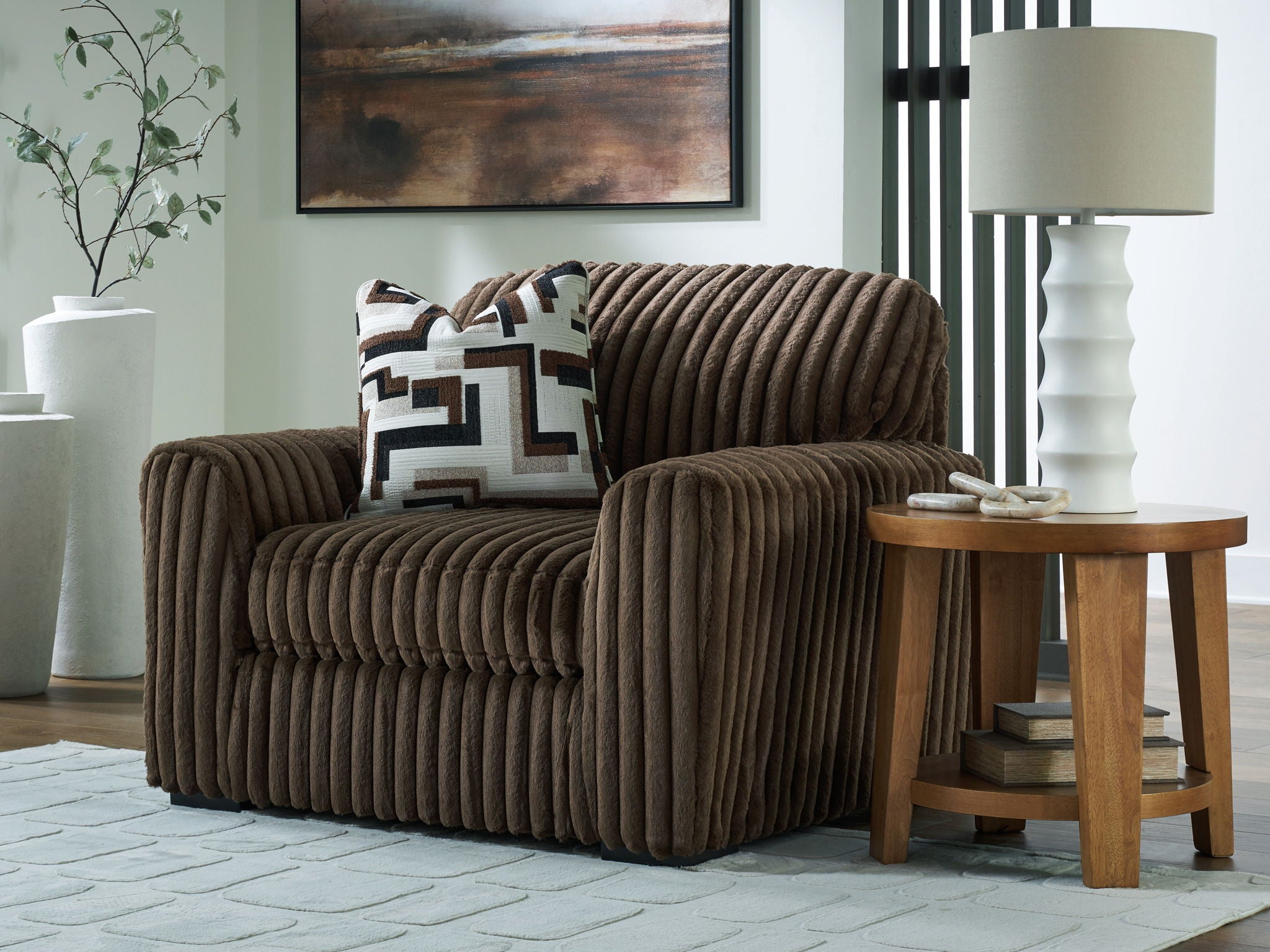 Dark brown chair and a half with patterned pillow and thick ribbed fabric