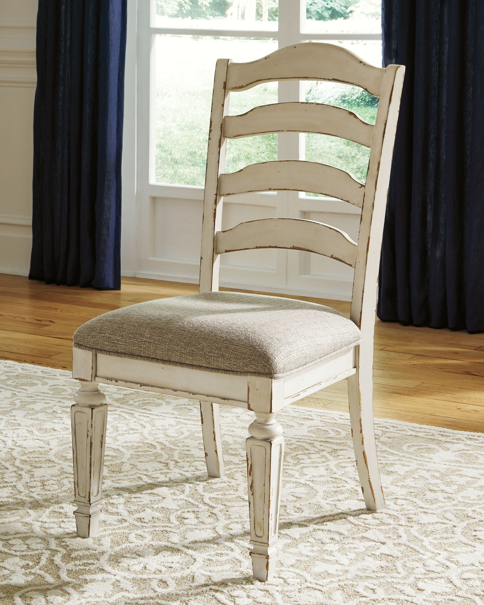 Chipped white ladderback dining side chair with gray upholstered seat, three-quarter view