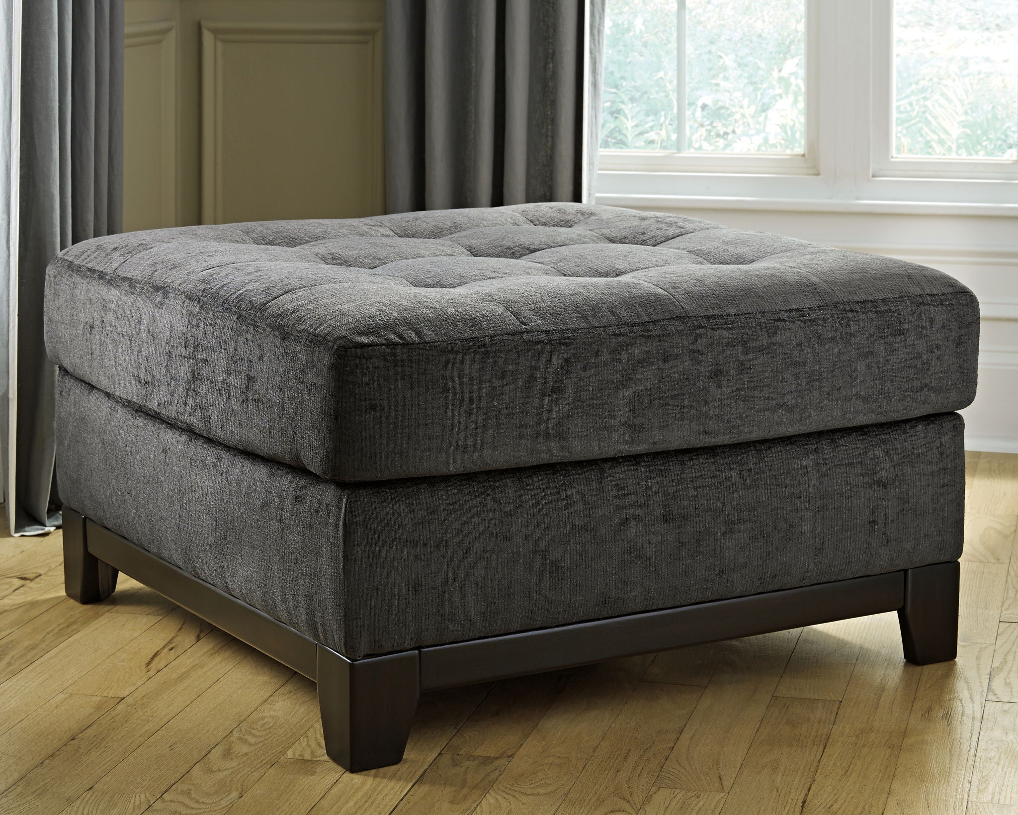 Oversized accent ottoman in dark gray upholstery with thick cushioned seat and legs