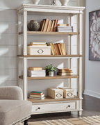 White wood bookcase with open shelves, brown panels, and two lower drawers.