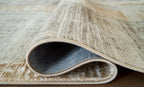 Beige area rug underside with bound edge and backing visible, flat weave