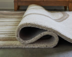 Rolled rug edge showing textured low pile with cream and dark stripe pattern
