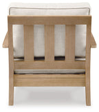 Beige lounge chair with cushion, vertical slat back and upholstered seat, light wood.