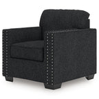Dark charcoal upholstered armchair with rolled back, wide arms, and silver nailhead trim.