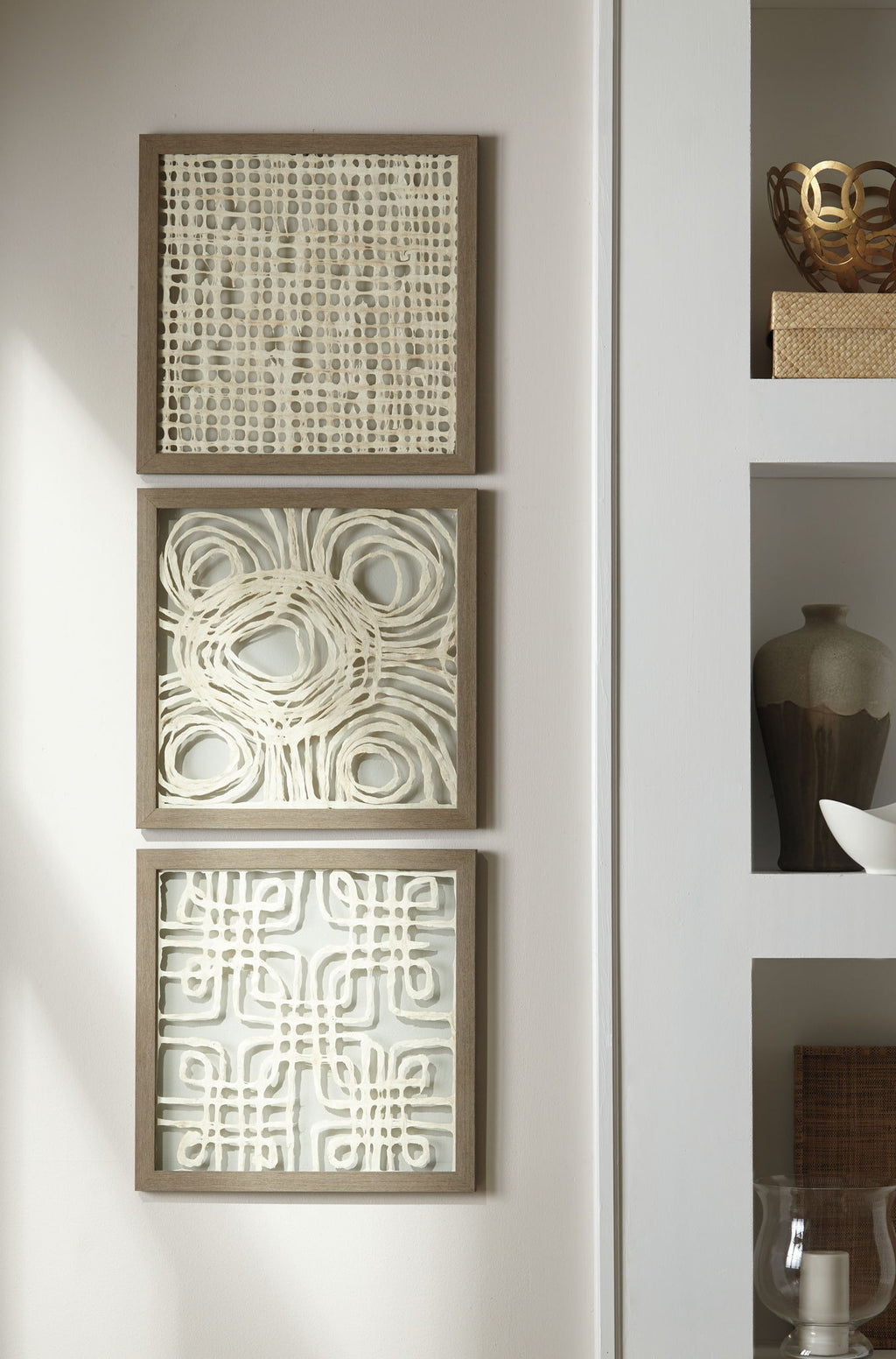 Three framed abstract wall art panels stacked on wall in cream tones with taupe frames.