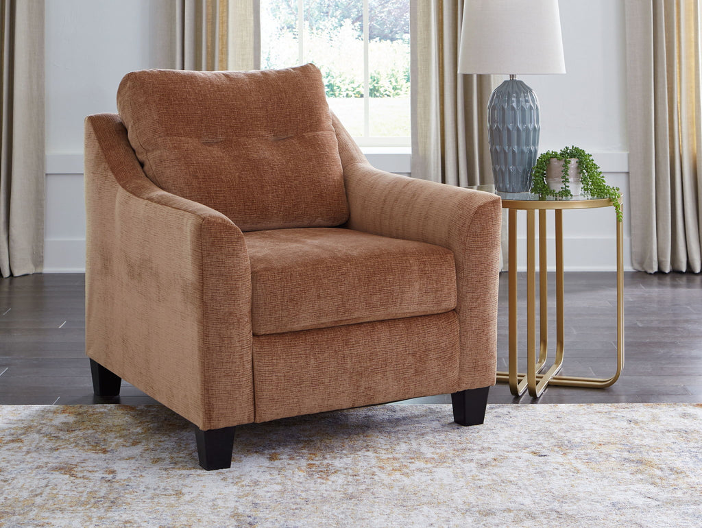 Brown accent chair with curved arms, upholstered back, and black wooden feet