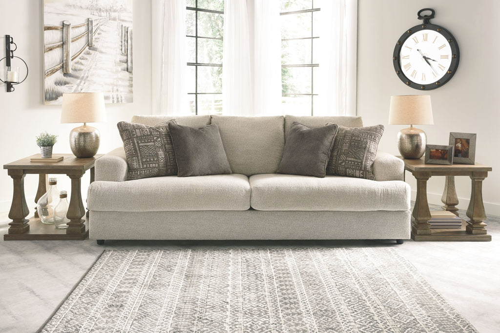 Beige fabric loveseat with three patterned throw pillows
