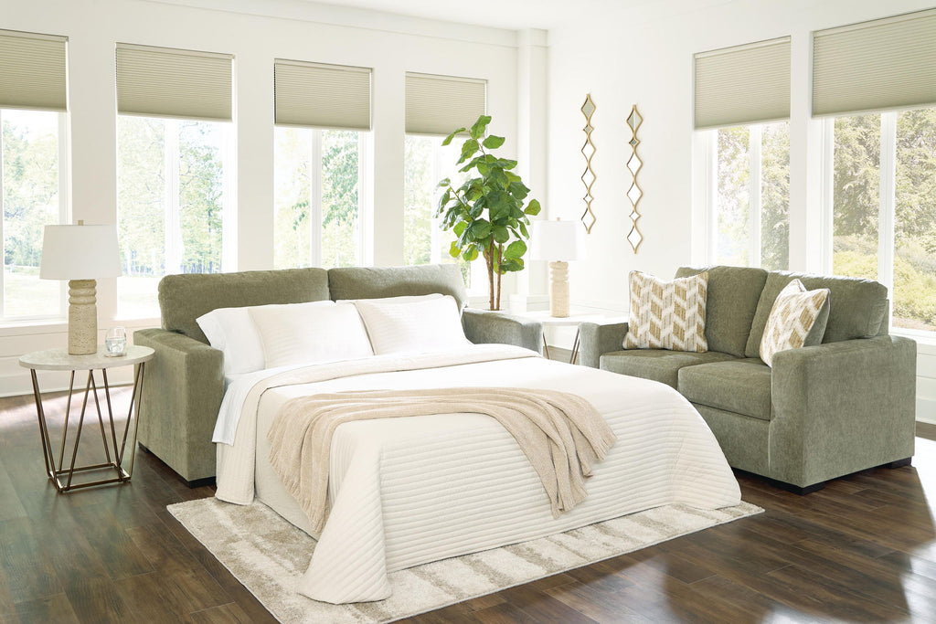 Green sofa sleeper with open seat view and white bedding and pillows