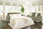 Green sofa sleeper with open seat view and white bedding and pillows