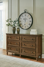 Brown wood dresser with eight drawers and metal knobs, straight apron and turned legs