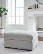 Light gray upholstered storage ottoman with hinged top and dark feet