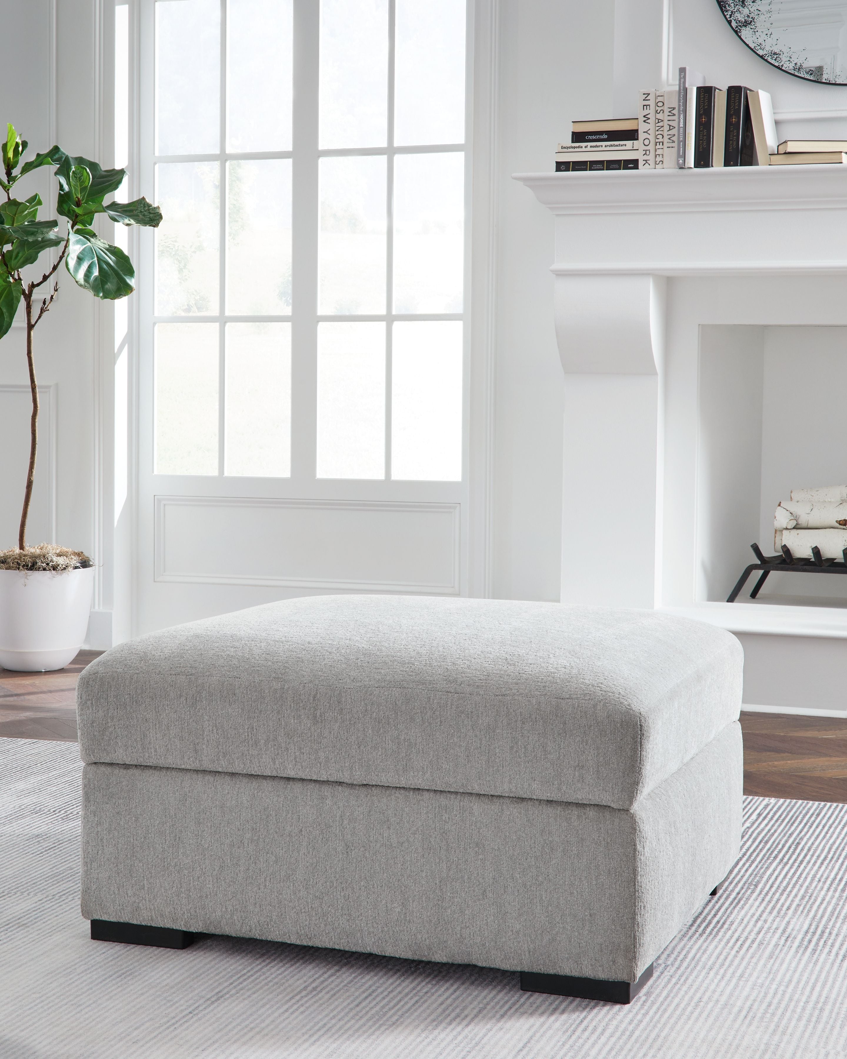 Light gray upholstered storage ottoman with hinged top and dark feet