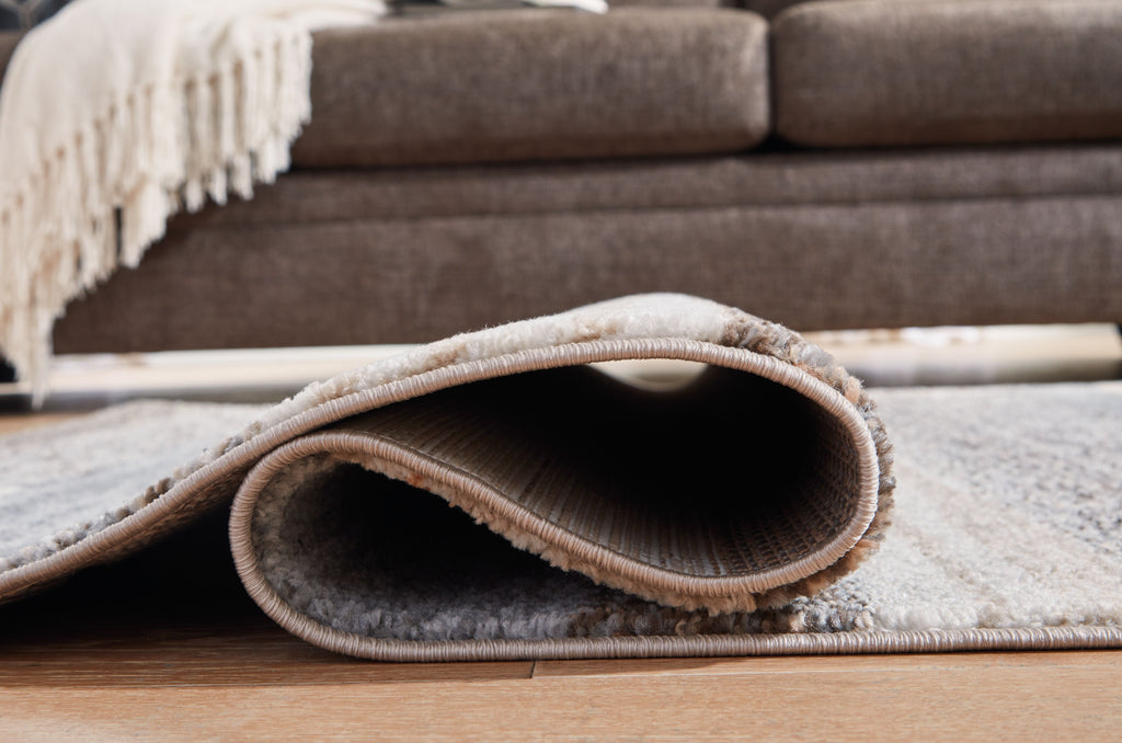 Gray rug corner with visible rounded edge binding and short pile